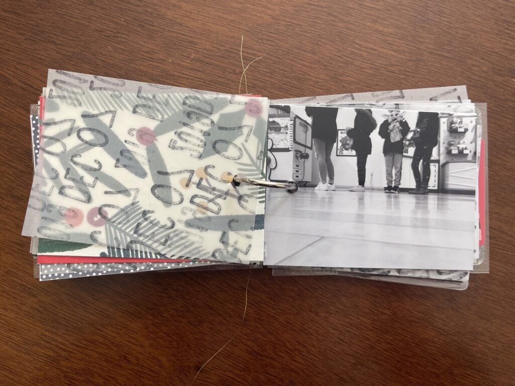 A spread from the album: the vellum page stamped with the date is flipped over to reveal and black-and-white photo of four kids in line to have their stuffed animals stuffed by the Build-A-Bear employee. 
