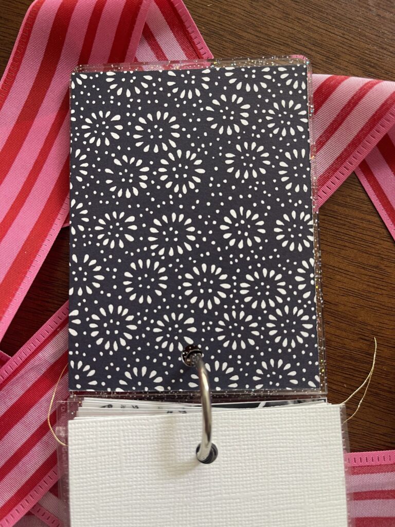 The back of the title page, made from a piece of a greeting card with a dark blue and white simple flower-like pattern.