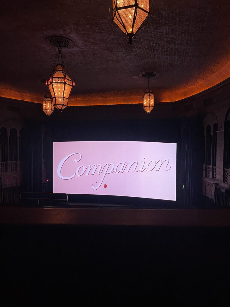 Movie screen at Bagdad Theater in Portland, OR, displaying the title of the movie "Companion," as seen from the balcony.