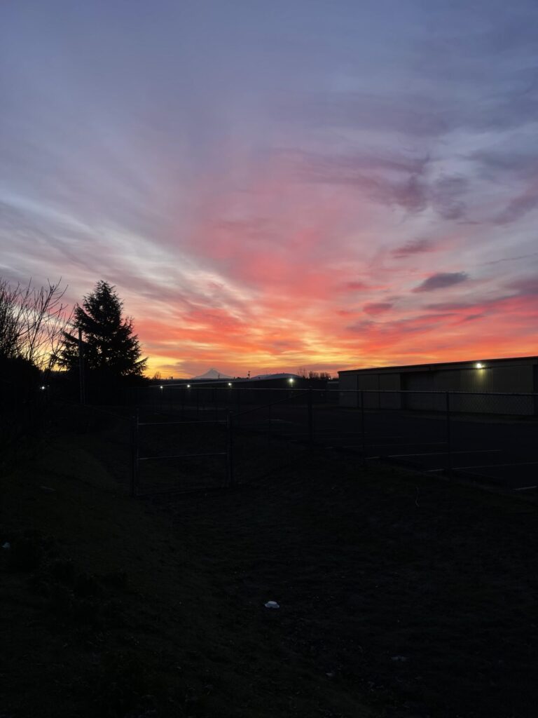 Cotton candy sunrise over Mount Hood with orange, yellow, and pink clouds. 