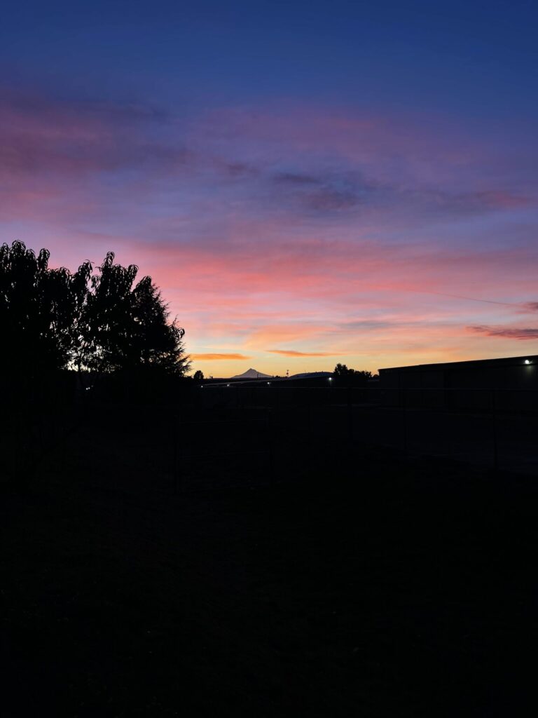 Sunrise over Mount Hood with yellow, orange, and pink clouds.