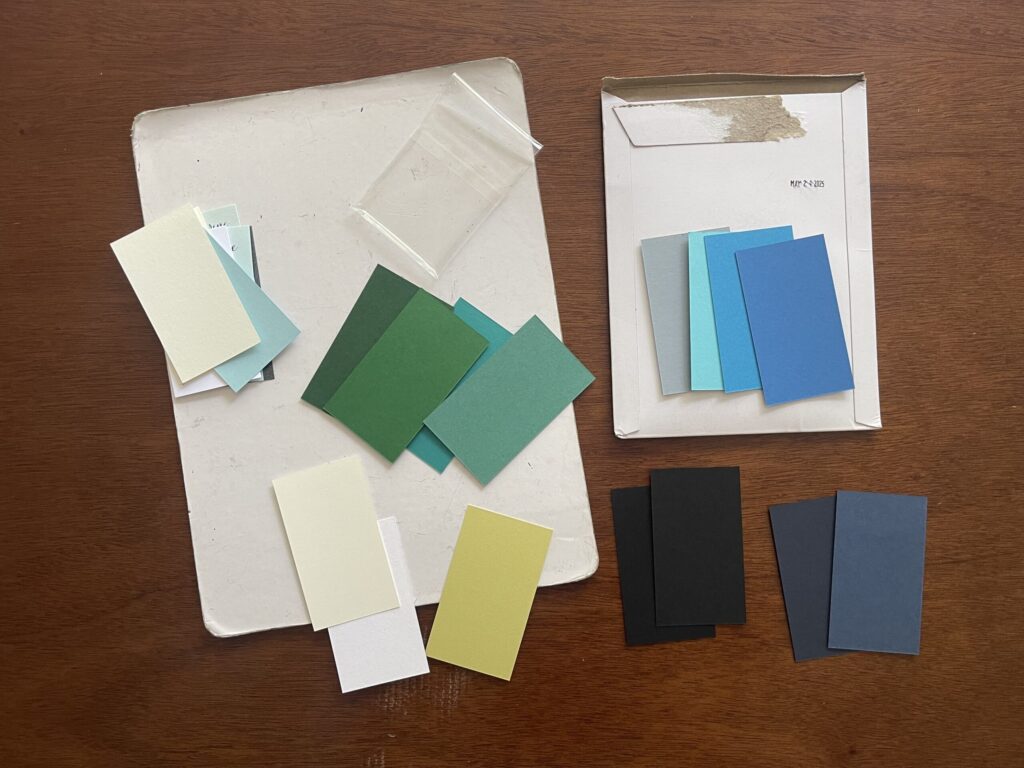 Paper samples in whites/creams, greens, blues, and blacks that are similar to the colors used in the show. 