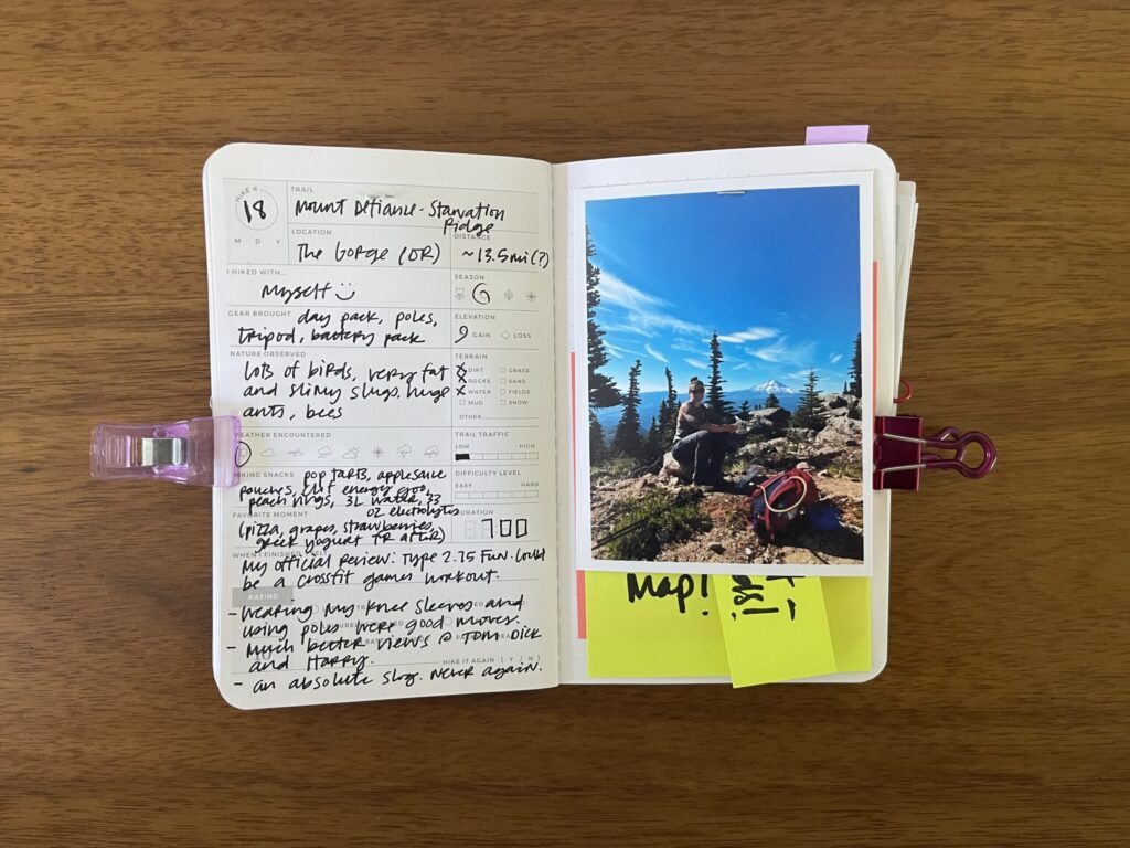 Spread of my hike of Mount Defiance and Starvation Ridge, an approximately 13.5-mile hike in the Columbia River Gorge, summer 2025. Details about the hike are written on the left page, a photo of me from the hike is on the right page, with the date of the hike stamped beneath it.
