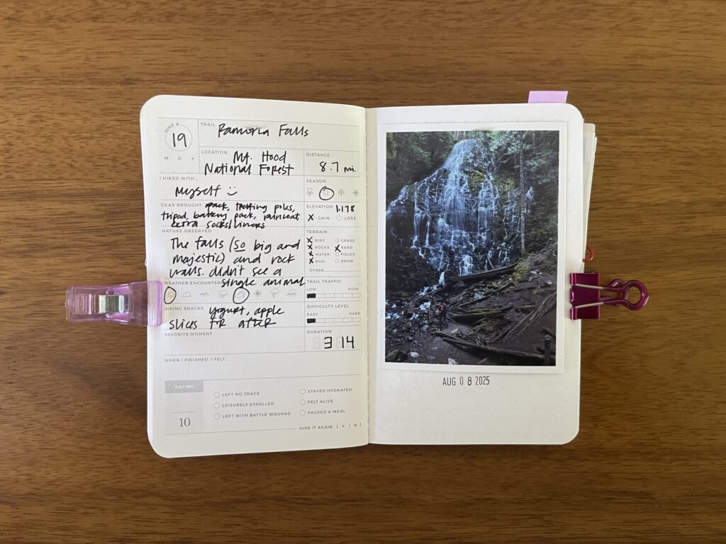 Spread of my hike of Ramona Falls, an 8.7-mile hike in Mt. Hood National Forest, summer 2025. Details about the hike are written on the left page, a photo of me from the hike is on the right page, with the date of the hike stamped beneath it.