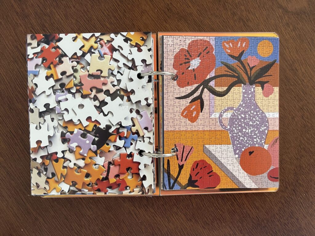Spread #2. The left-hand page is a photo of the puzzle's unpuzzled pieces. The right-hand page is a photo of the completed puzzle of illustrations of flowers in a vase on a counter in front of a window.