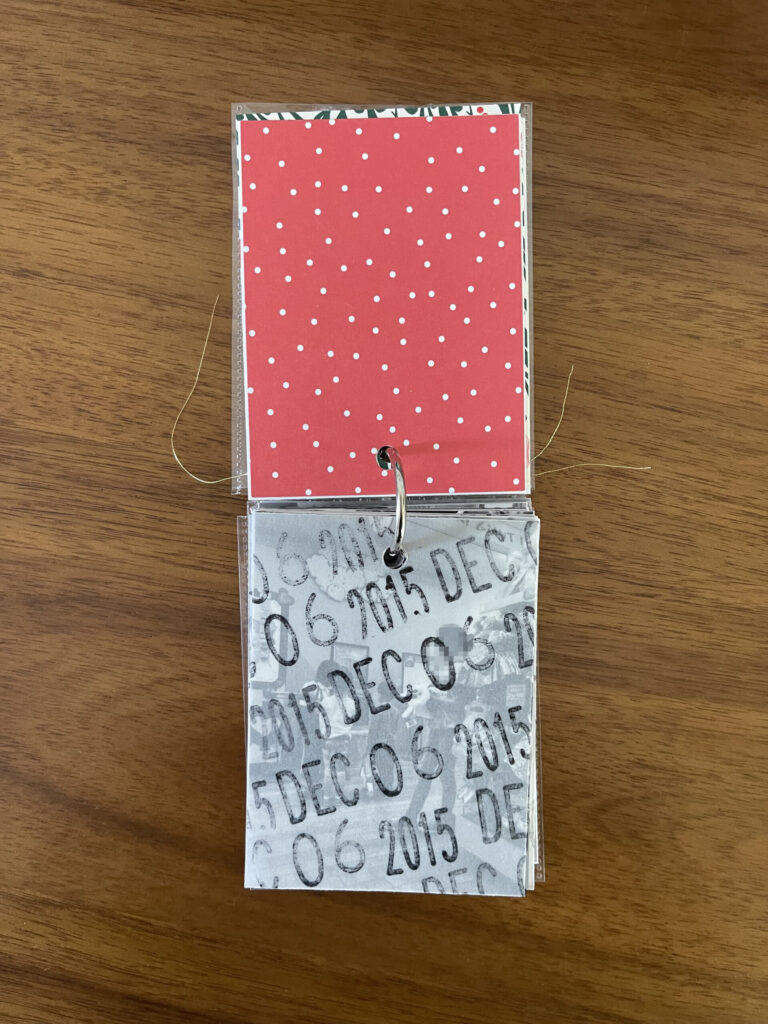 2015. The top page is a piece of patterned paper. The bottom page is a piece of vellum stamped repeatedly with the date. Beneath the vellum is a black-and-white photo from that year's visit. 