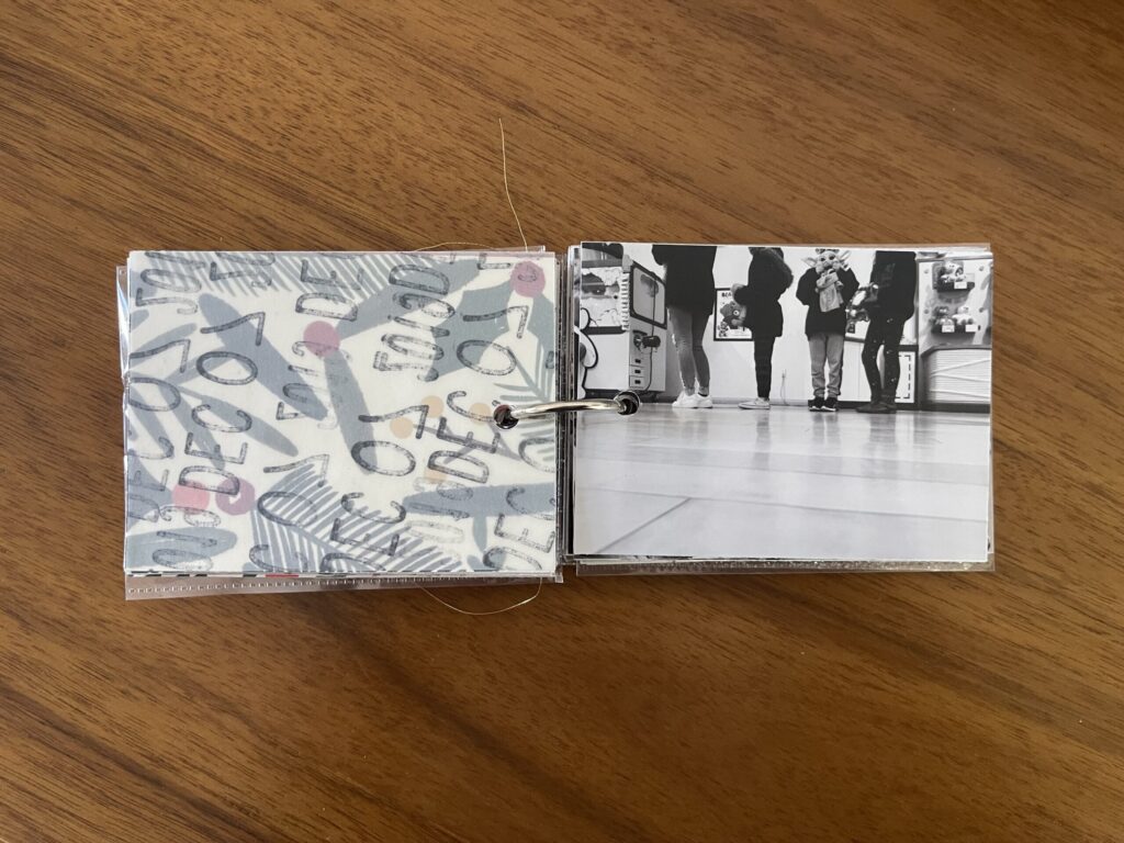 2019: the vellum page stamped with the date is flipped over to reveal and black-and-white photo of four kids in line to have their stuffed animals stuffed by the Build-A-Bear employee. 