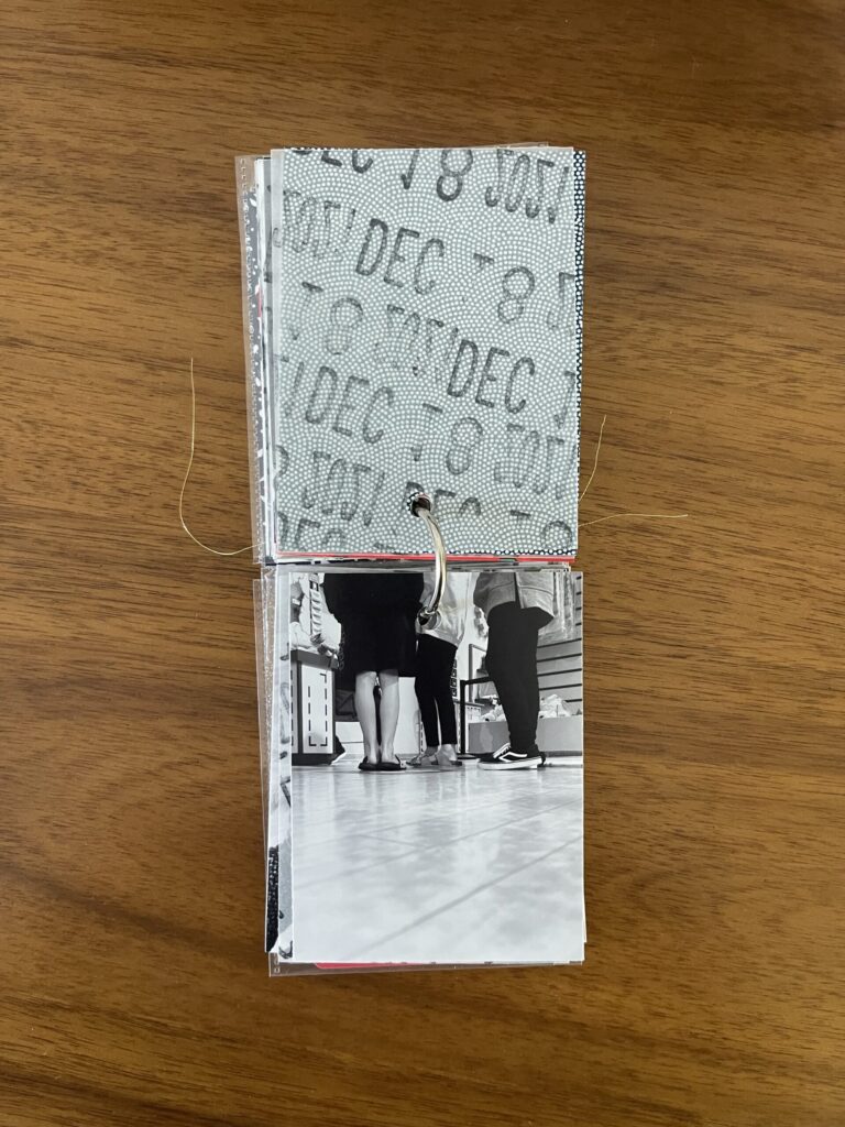 2021: the vellum page stamped with the date is flipped over to reveal a black-and-white photo of three kids in line to have their stuffed animals stuffed by the Build-A-Bear employee. 