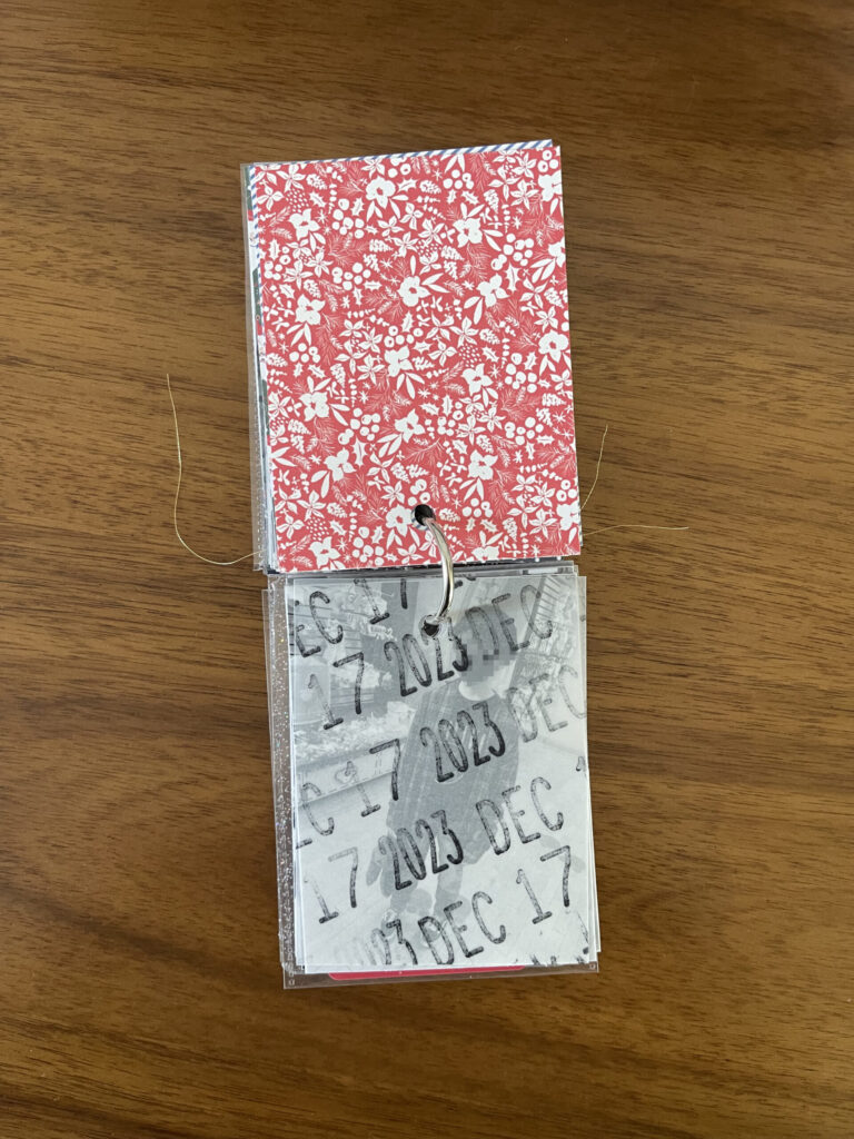 2023. The top page is a piece of patterned paper. The bottom page is a piece of vellum stamped repeatedly with the date. Beneath the vellum is a black-and-white photo from that year's visit. 