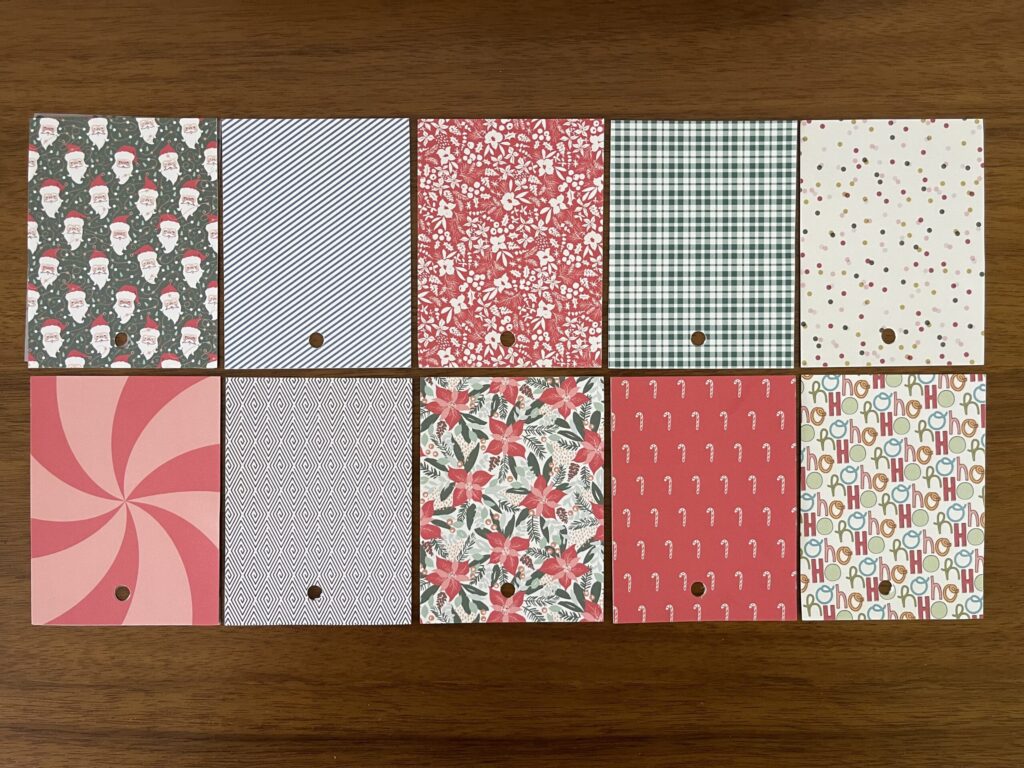 Various holiday-themed papers cut down to 3 inches by 4 inches and arranged in two rows. 